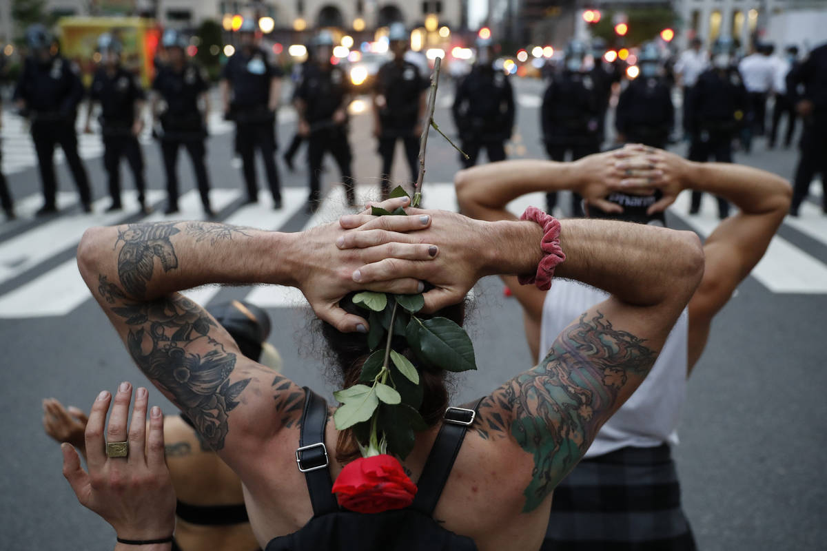 Protesters kneel in front of New York City Police Department officers before being arrested for ...