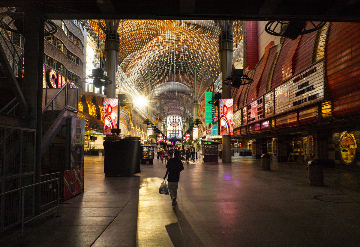 People walk around the Fremont Street Experience as hotel-casinos reopen in downtown Las Vegas ...