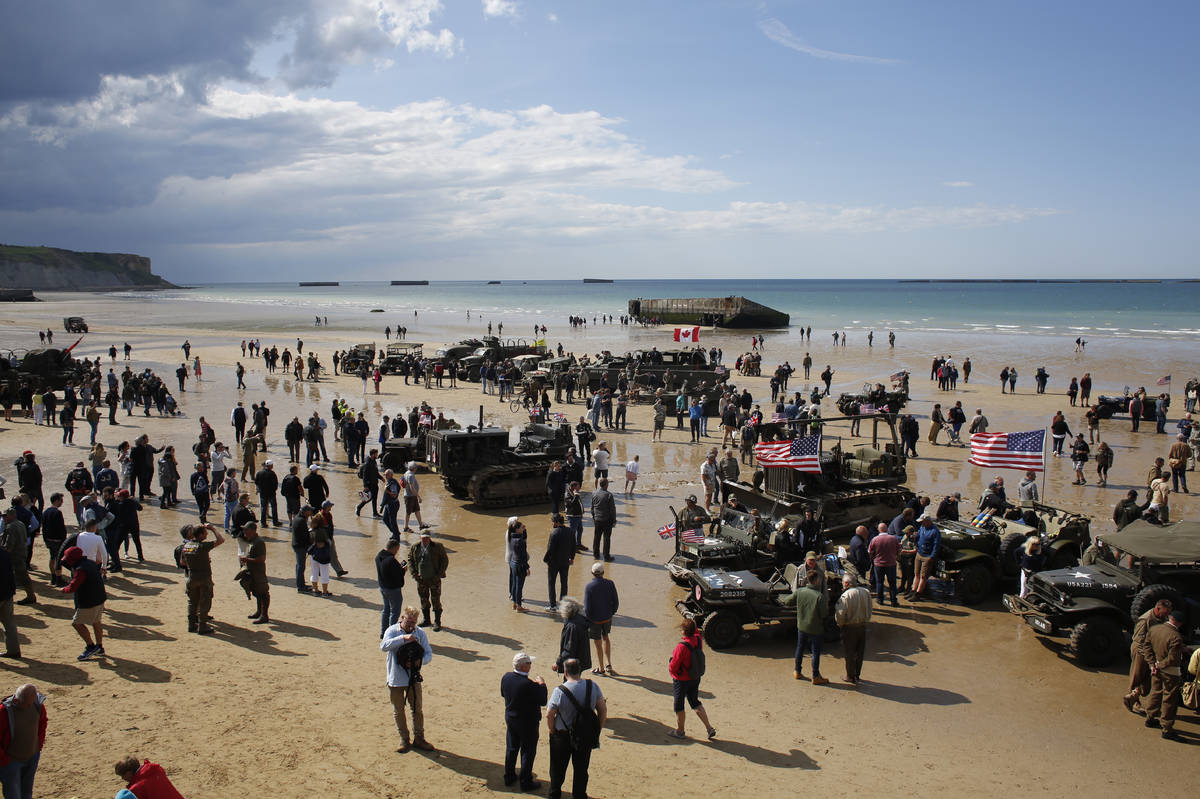 FILE - In this Thursday, June 6, 2019 file photo, people walk among vintage World War II vehicl ...