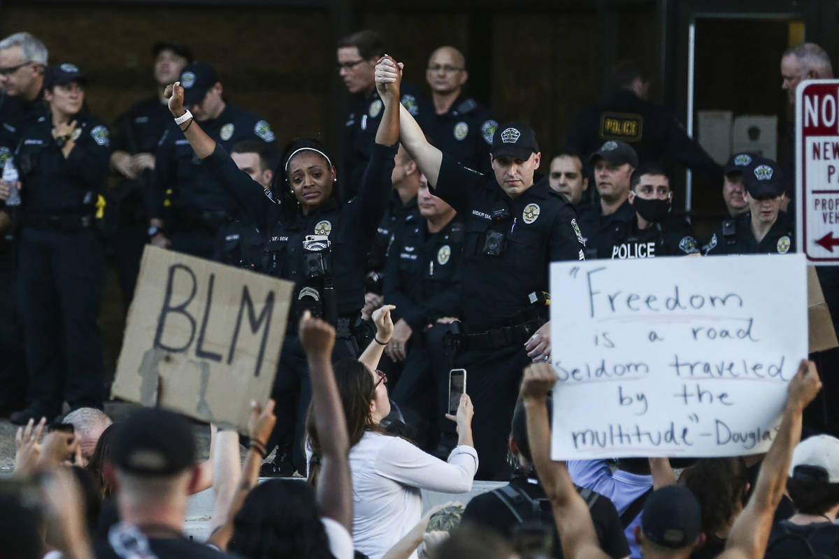 APD officer Alexandra Parker holds her hand up with a fellow officer as they kneel together wit ...