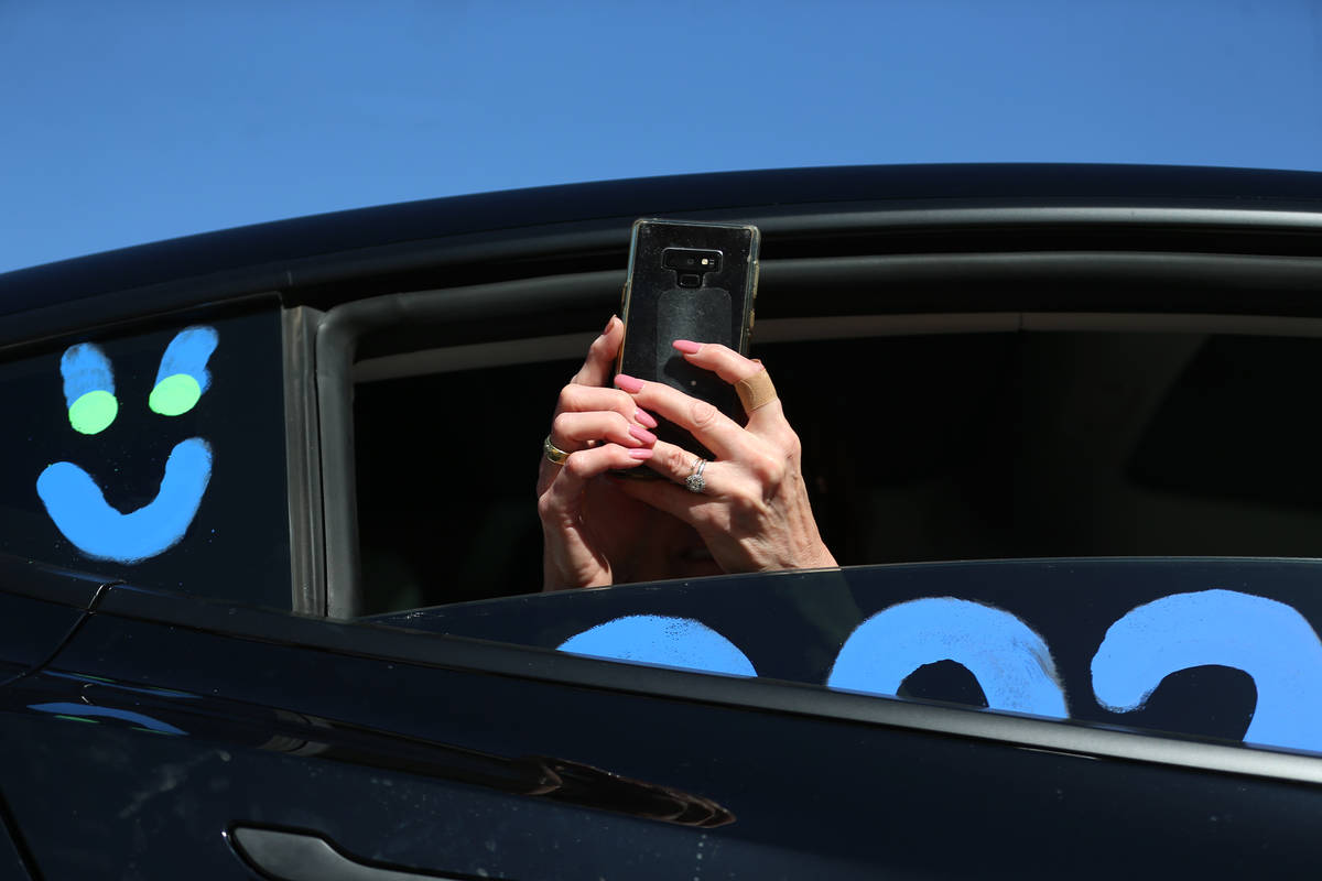 A person take a photo from a car during the Las Vegas Academy drive-through graduation in Las V ...