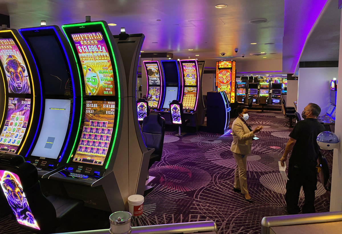 Slot machines and players at Harrah's are staged for social distancing as they are open for bus ...