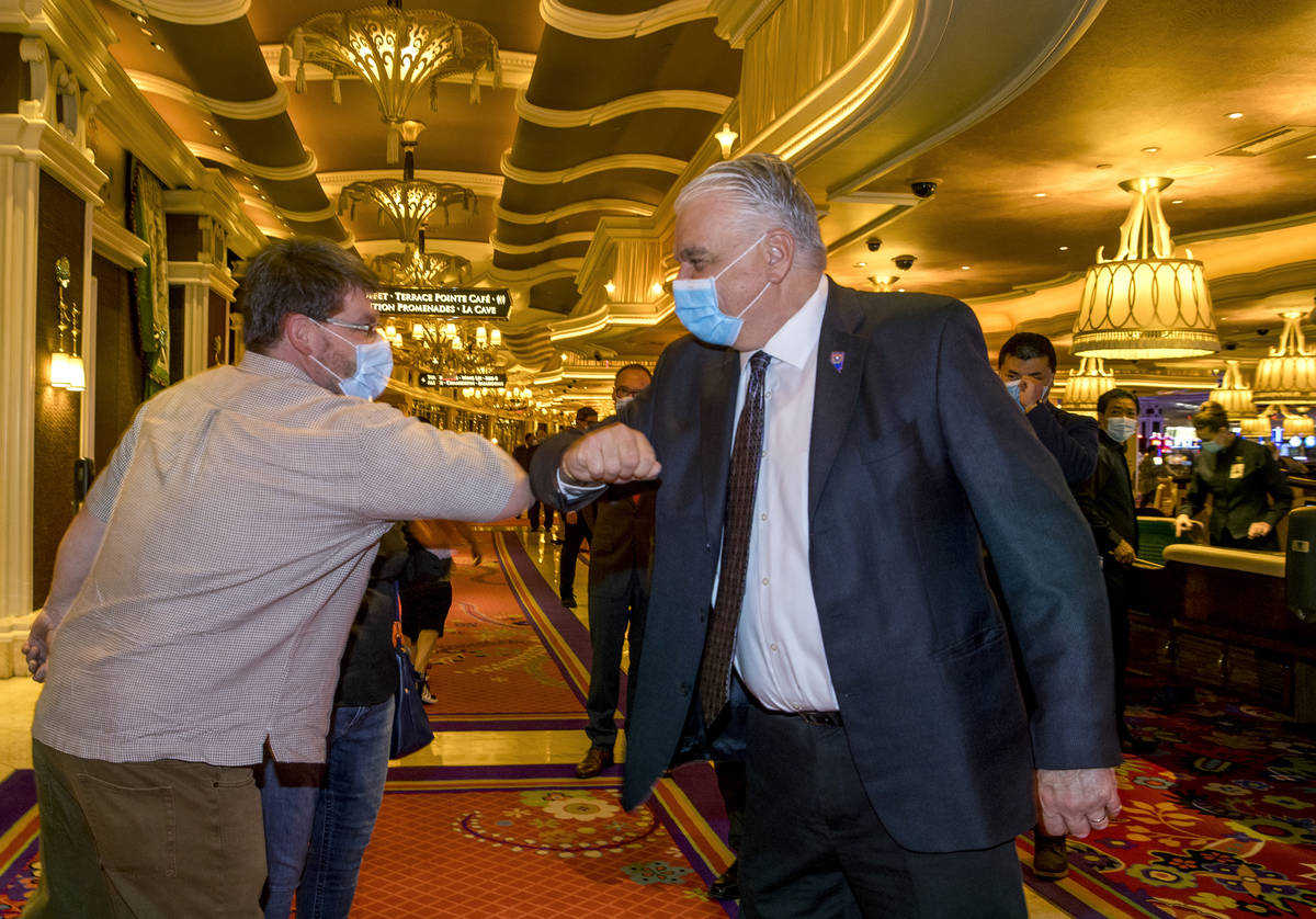 A Wynn Las Vegas guest gives an elbow bump to Gov. Steve Sisolak during his tour to view their ...