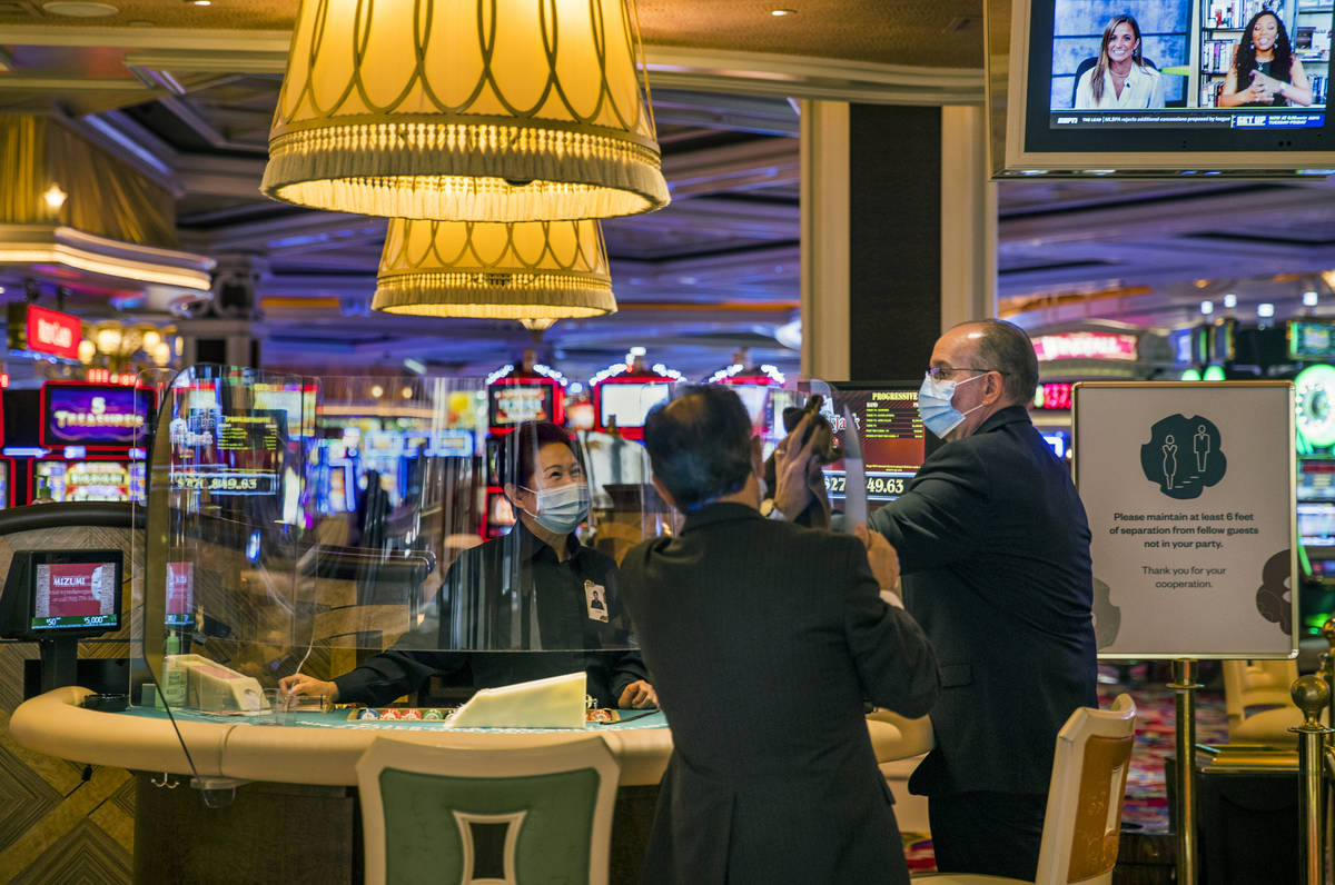 Wynn Las Vegas employees clean the plexiglass at one of their tables while Gov. Steve Sisolak t ...