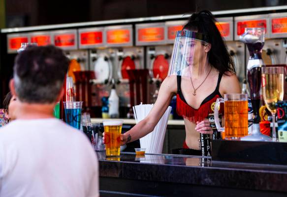 A bartender at the D Las Vegas wears a face shield while serving drinks at the Fremont Street E ...