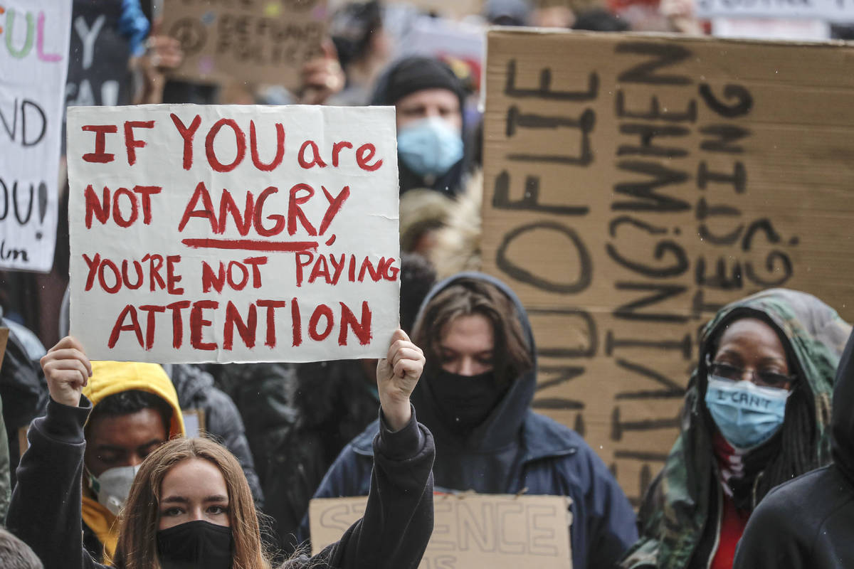 People hold placards during a Black Lives Matter rally in Parliament Square in London, Saturday ...