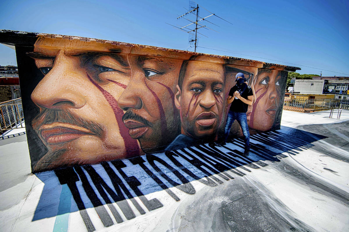 Street artist Jorit poses next to his last work, a mural honoring George Floyd, who died May 25 ...