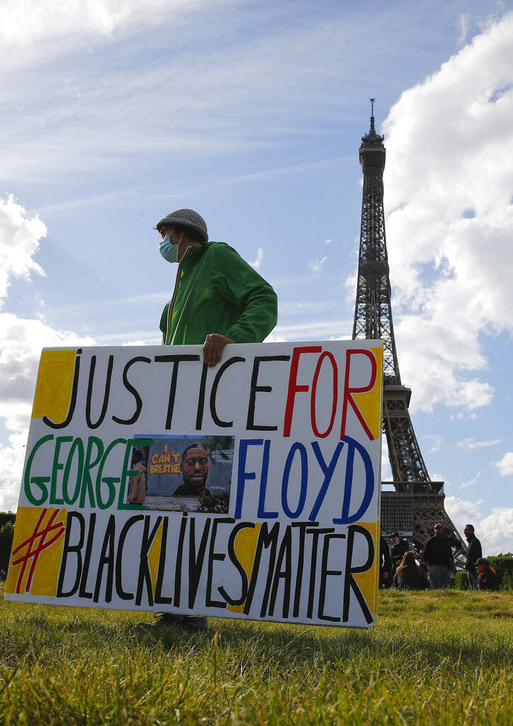 A demonstrator holds a placard on Champs de Mars as the Eiffel Tower is seen in the background ...