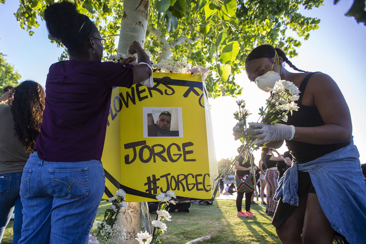 Protesters place flowers around a poster of a man killed by police during a press conference ho ...