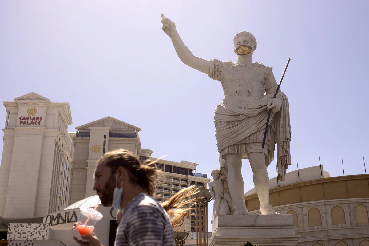 Pedestrians walk past a masked statue in front of Caesars Palace on the third day that the Stri ...