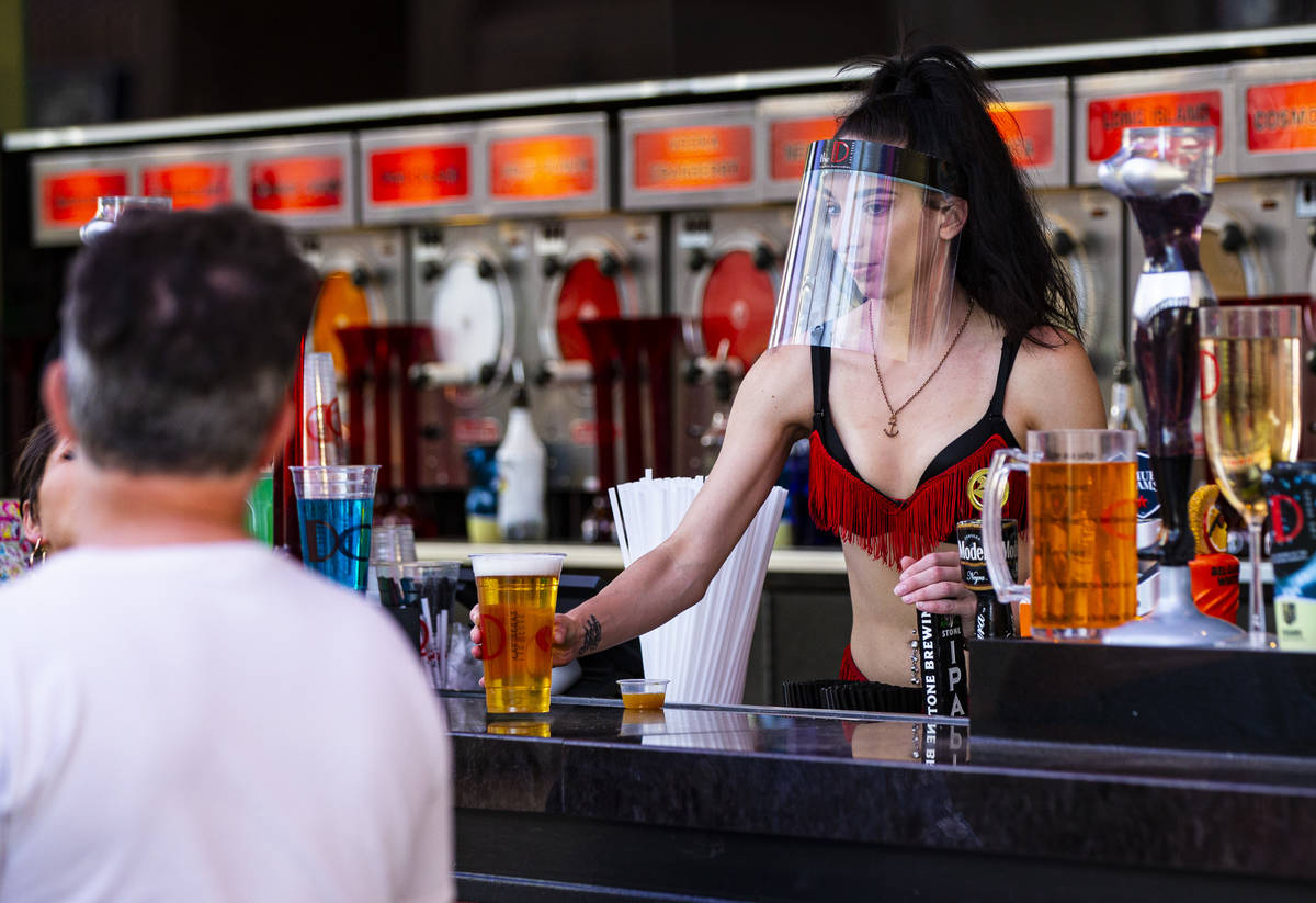 A bartender at the D Las Vegas wears a face shield while serving drinks at the Fremont Street E ...