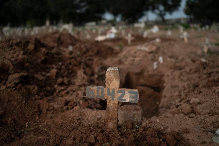 A cross marks the grave of 57-year-old Paulo Jose da Silva, who died from the new coronavirus, ...