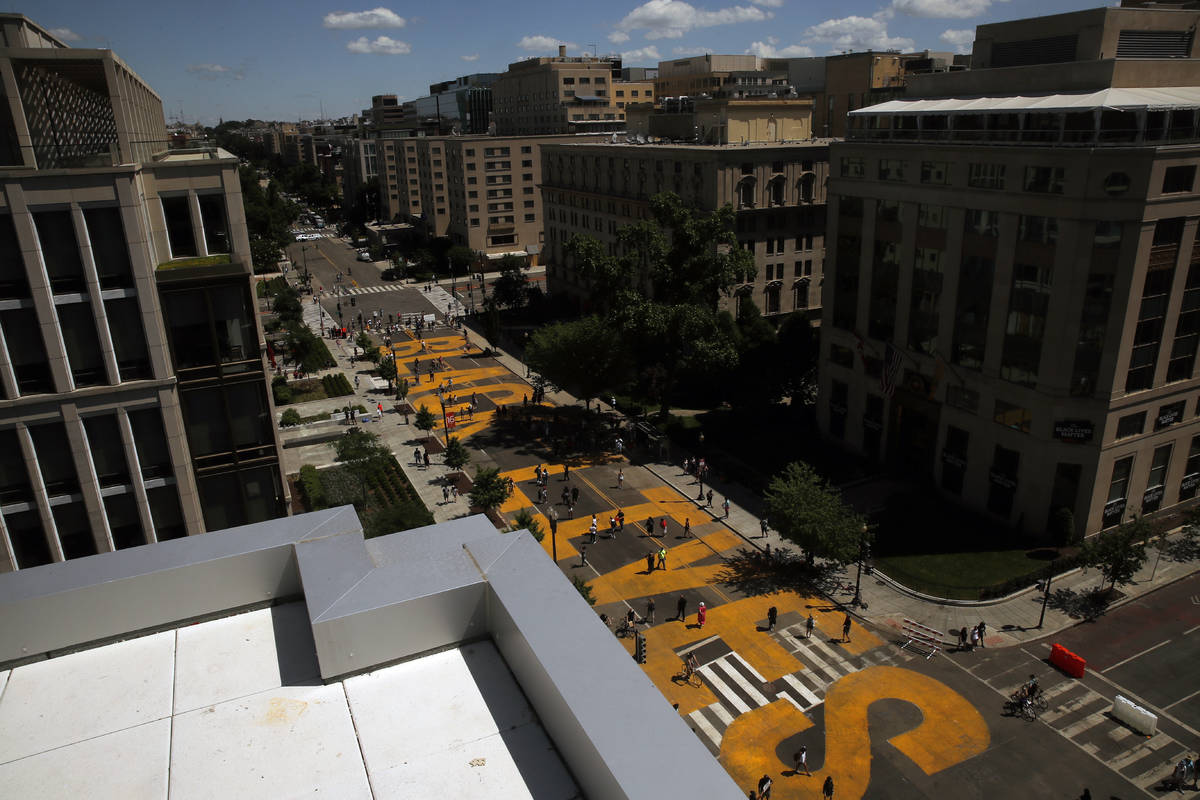 People walk on the words Black Lives Matter that was painted in bright yellow letters on 16th S ...
