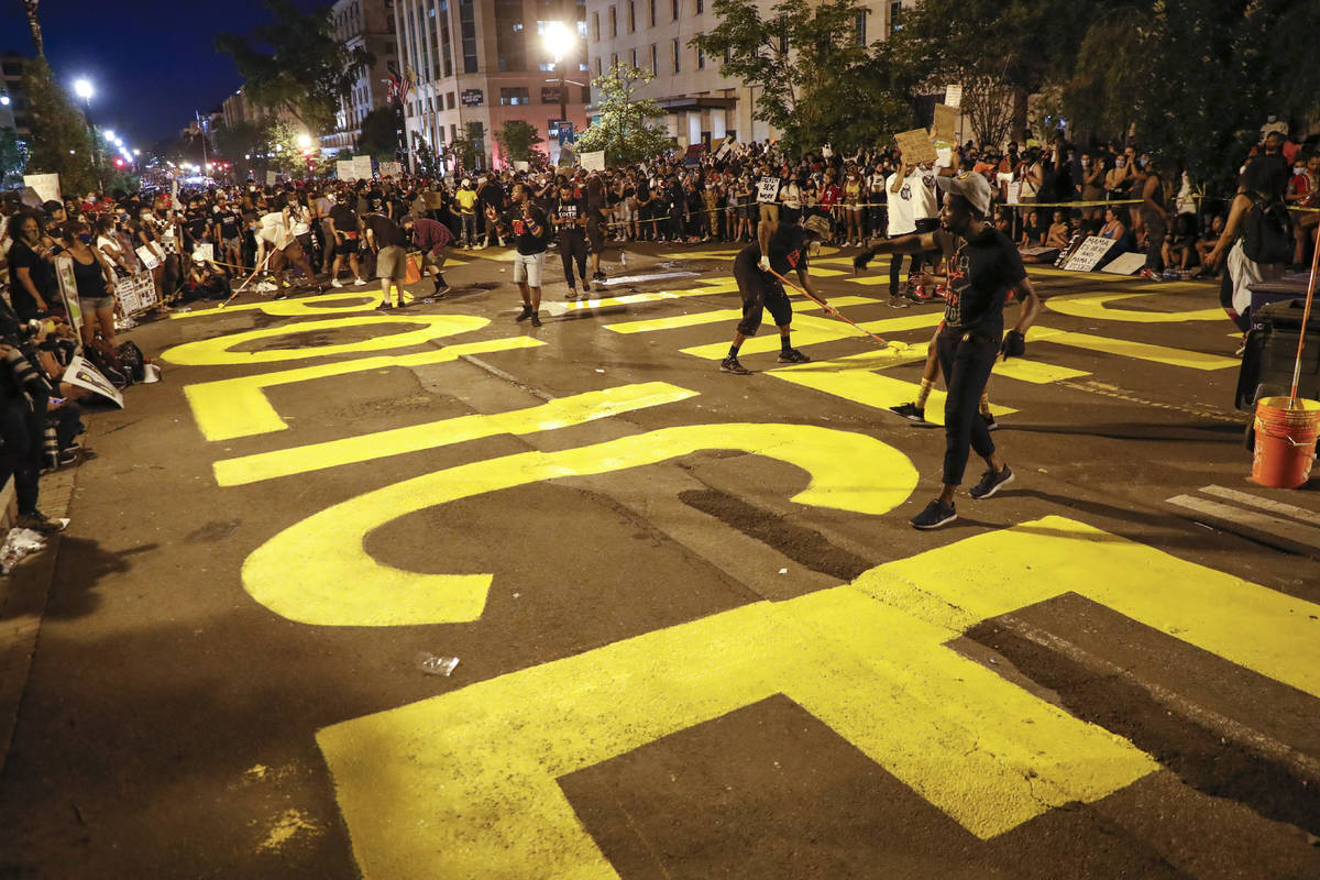 Demonstrators paint the words 'defund the police' as they protest Saturday, June 6, 2020, near ...