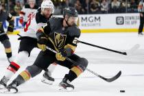 Vegas Golden Knights defenseman Shea Theodore (27) skates around New Jersey Devils center Travi ...