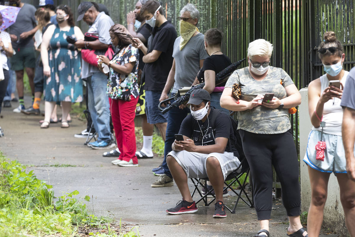 Steven Posey checks his phone as he waits in line to vote, Tuesday, June 9, 2020, at Central Pa ...