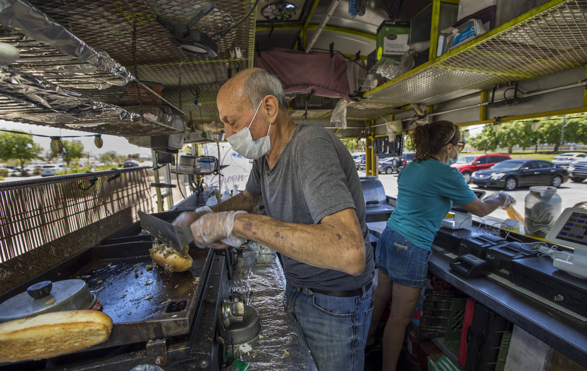 Ron Gradinger, left, of the Hot Diggity Dog Las Vegas prepares another Philly Cheesesteak as Je ...