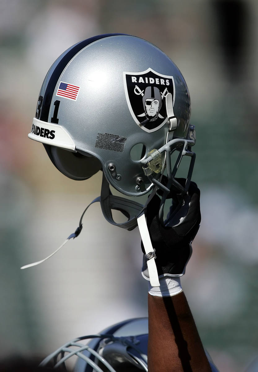 An Oakland Raiders player holds up a helmet at the start of a NFL preseason football game again ...