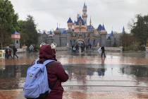 A visitor stands in the rain at Disneyland in Anaheim, Calif., Friday, March 13, 2020. Disneyla ...