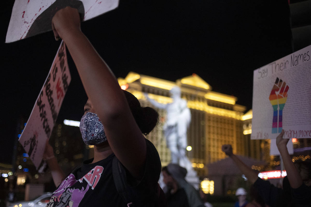 Protesters pause for street lights outside Caesars Palace during a protest against police bruta ...