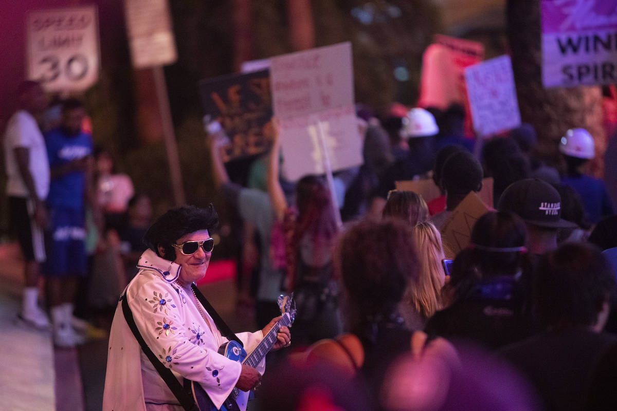 An Elvis impersonator interacts with protesters as they pass by during a protest against police ...