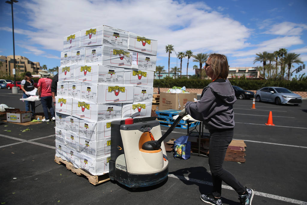 Three Square Food Bank warehouse assistant Kari Guerrero moves boxes of fresh fruit to give out ...