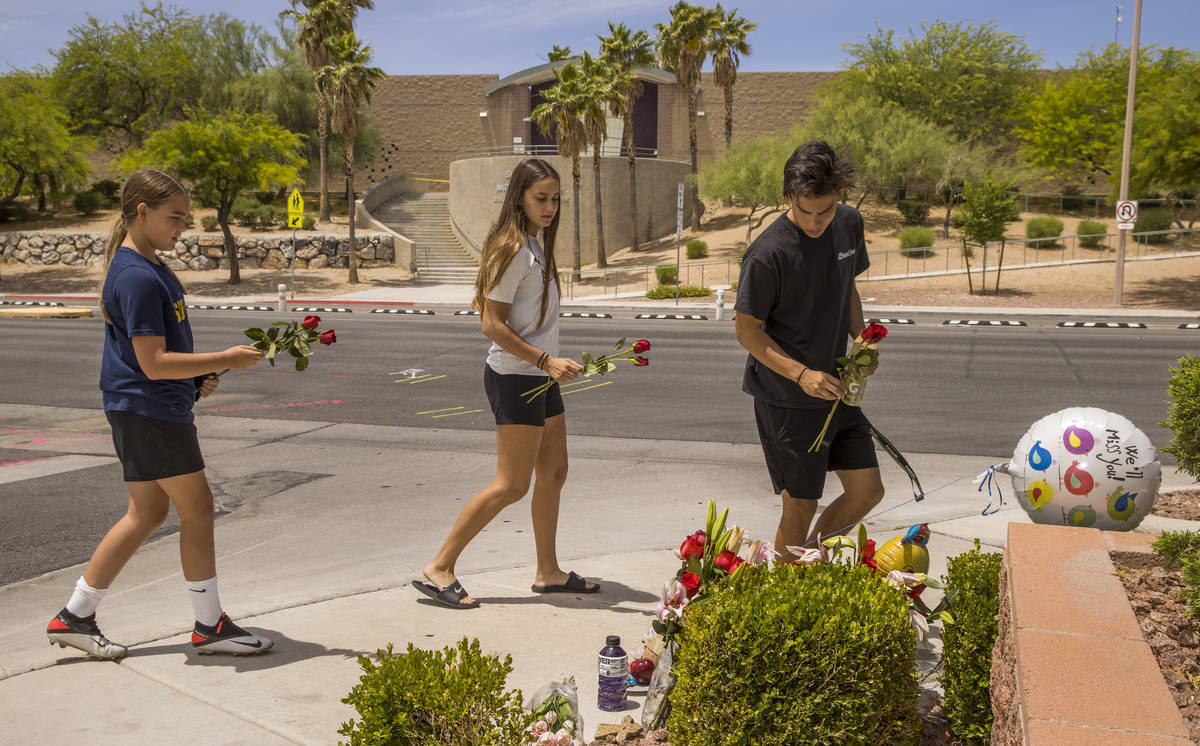 Former classmates stop by to leave roses at a small memorial near where two teen brothers were ...