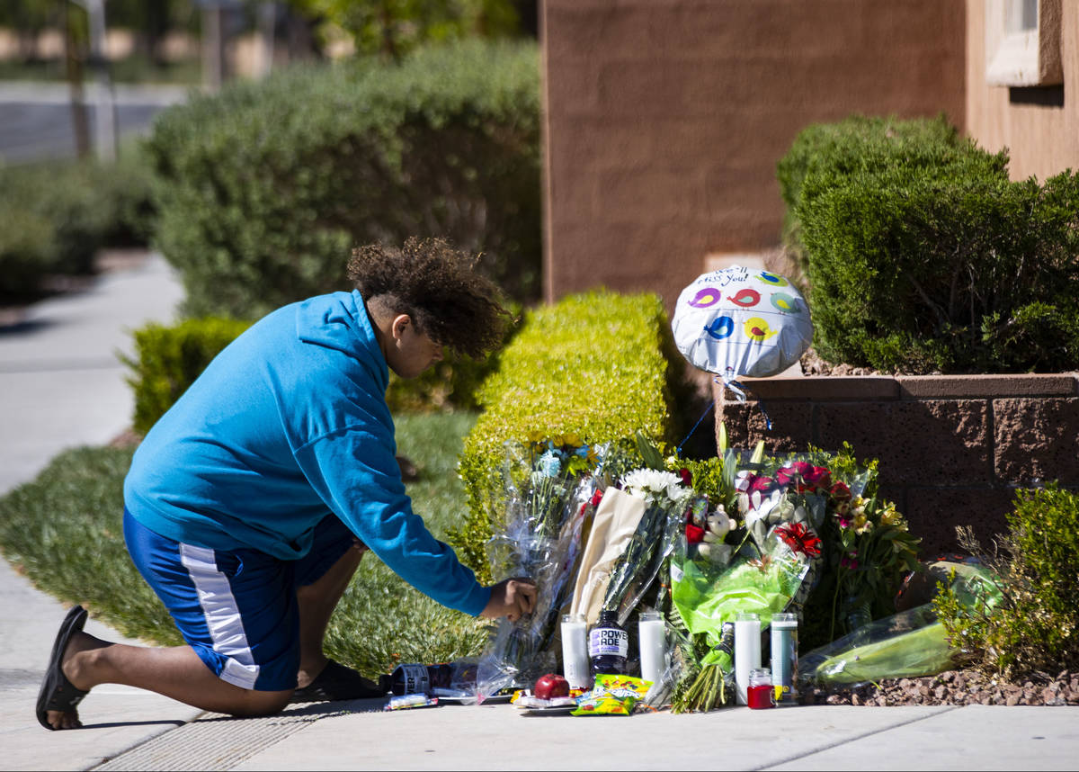 John Taylor, 14, helps arrange items left at the memorial left for David Cox, 18, and Brandon C ...