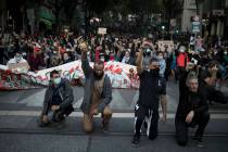 Protesters raise their fists and kneel in front of French riot police during a march against po ...