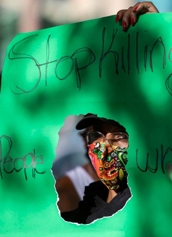 One protester holds a sign reading "Stop killing people who look like me" as the prot ...