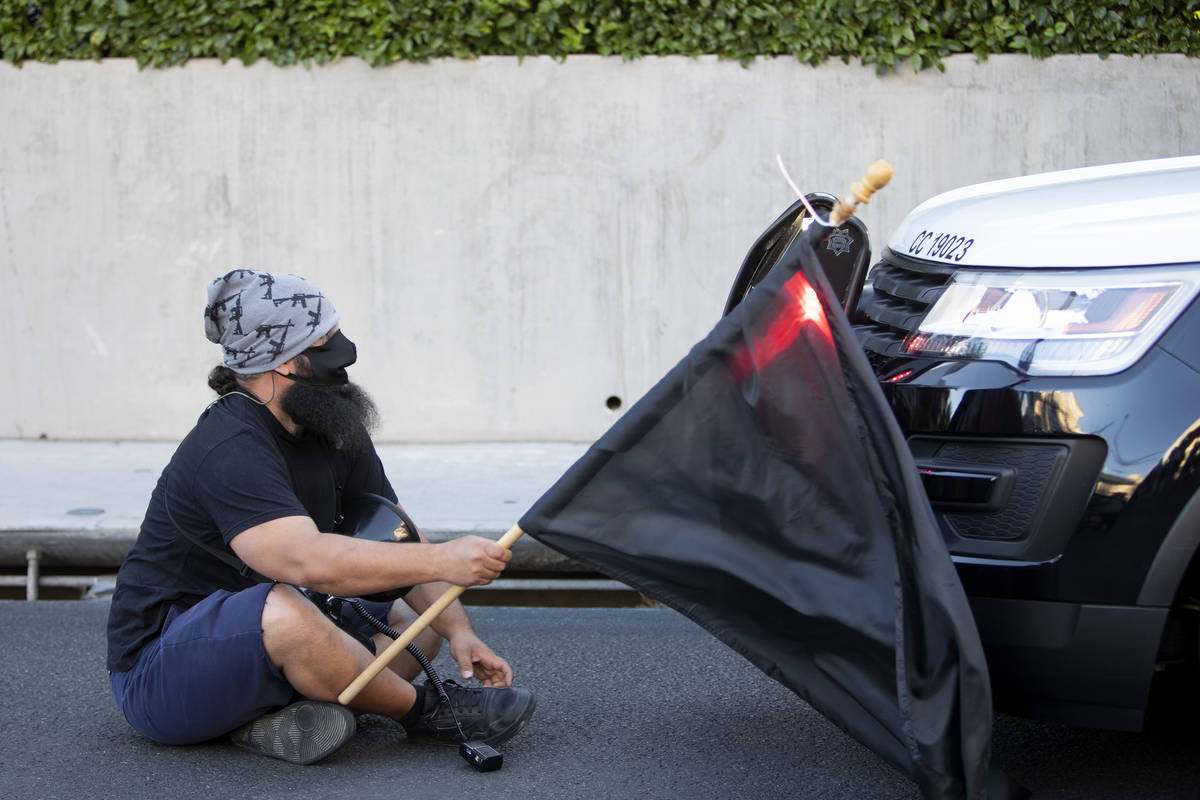 One protester sits in front of a police squad car during a protest against police brutality tha ...