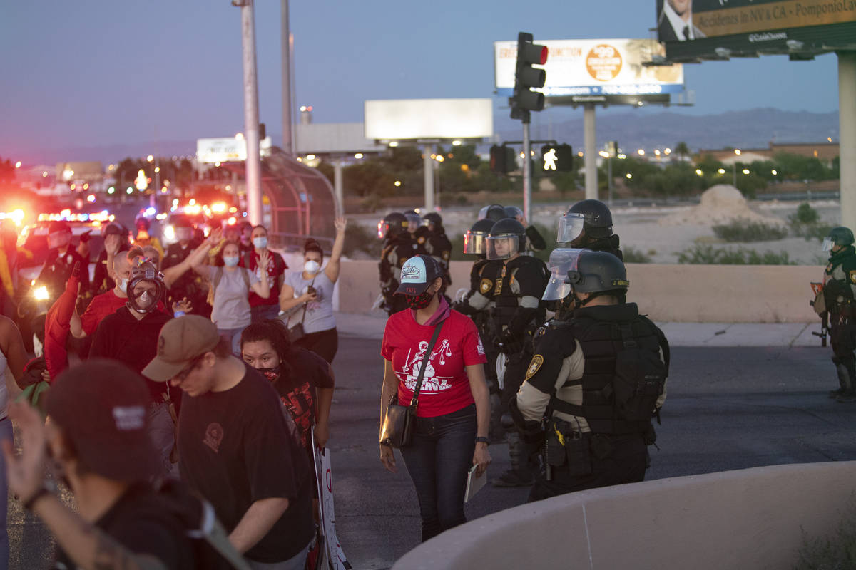Protesters pass police at an intersection with their hands up on Saturday, June 13, 2020 in Las ...
