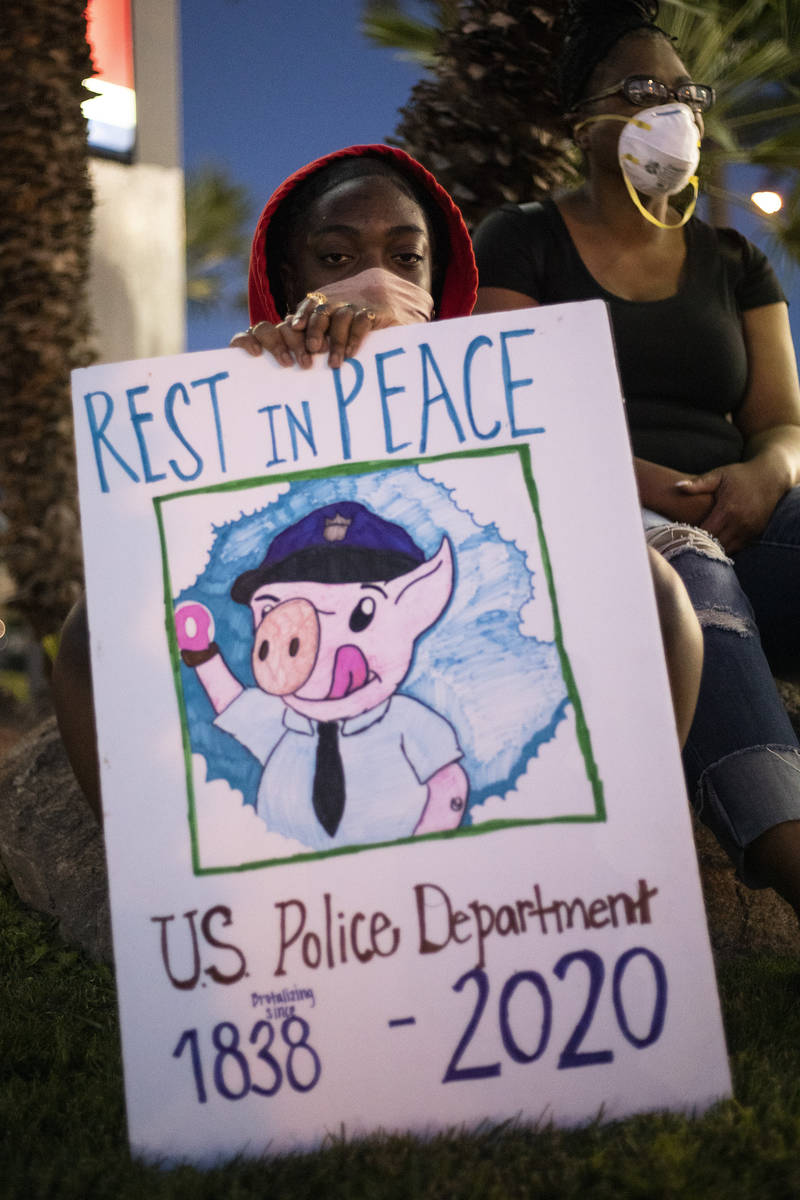 While waiting for a ride following a protest against police brutality, Avi Fielder holds up a s ...