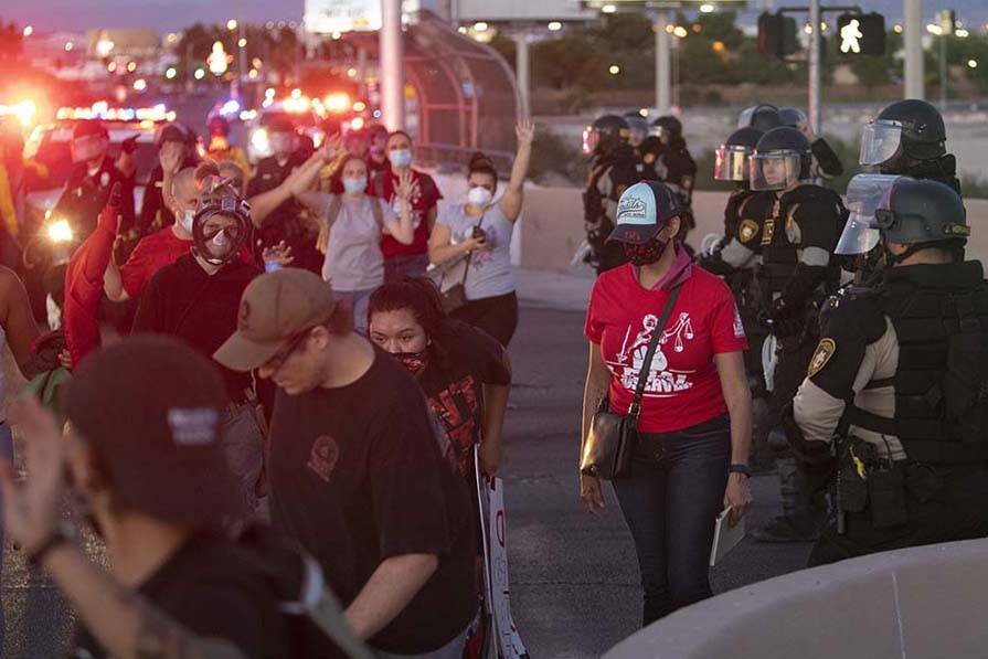 Protesters pass police at an intersection with their hands up on Saturday, June 13, 2020 in Las ...