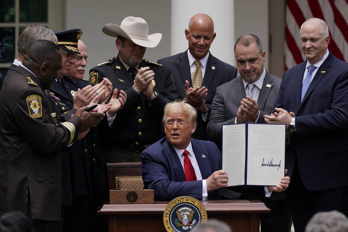 Law enforcement officials applaud after President Donald Trump signed an executive order on pol ...