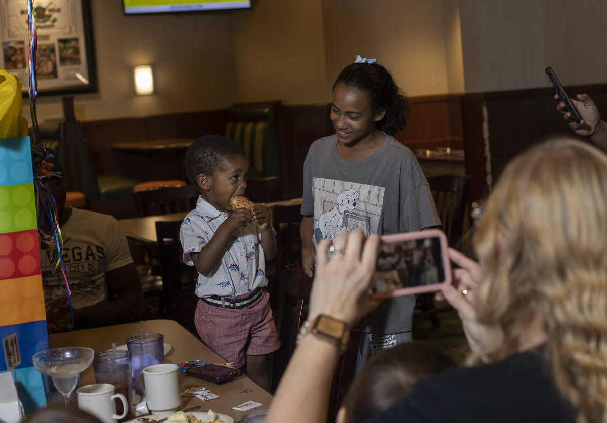 Kyrie Williams, 2, takes a bite while his family and friends sing him happy birthday at John's ...