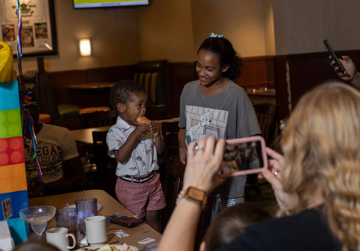 Kyrie Williams, 2, takes a bite while his family and friends sing him happy birthday at John's ...