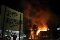 "RIP Rayshard" is spray painted on a sign as as flames engulf a Wendy's restaurant du ...