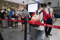 Airline employees redirect a traveller at a checkpoint for passengers from high risk areas to p ...