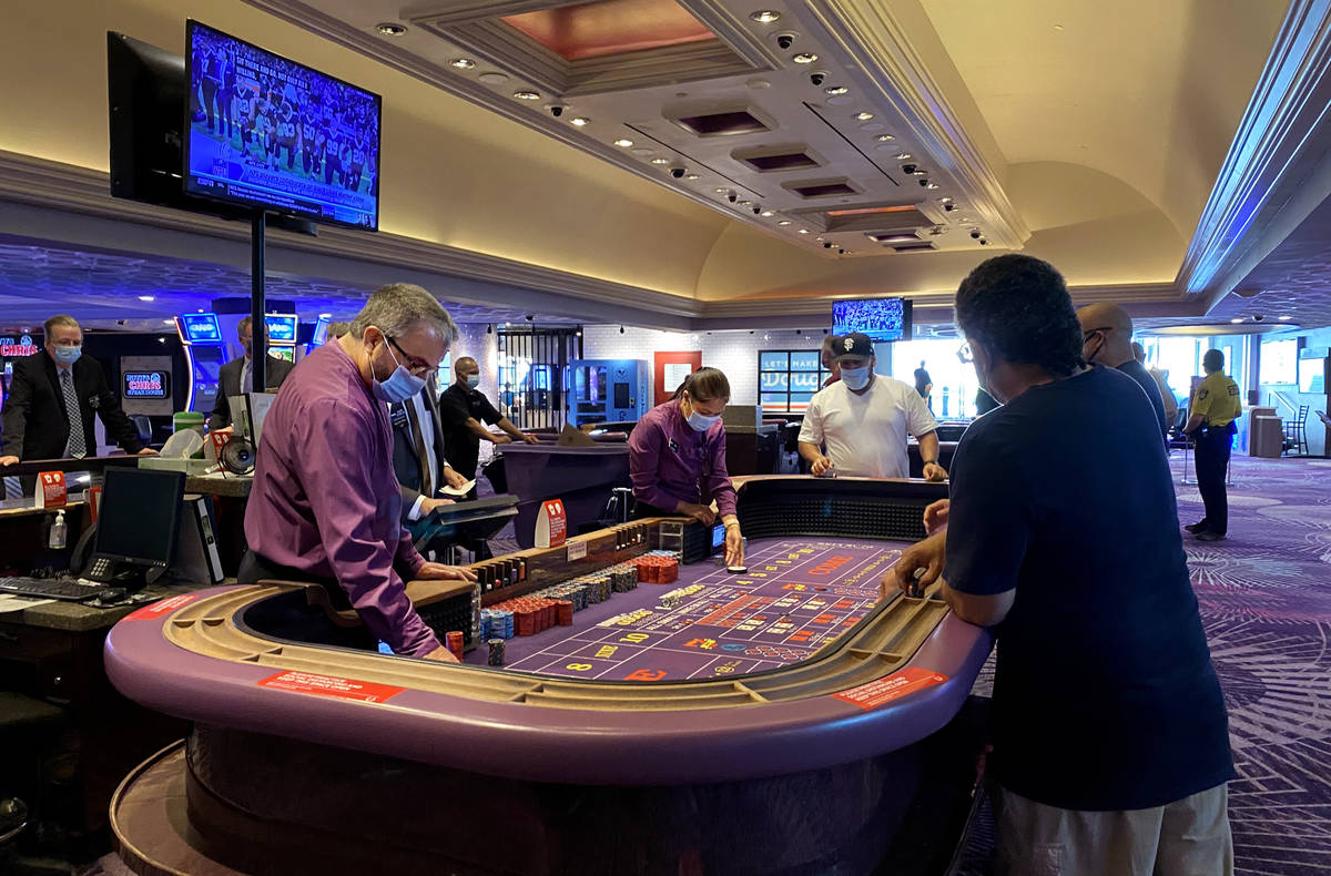 Guests play craps at Harrah's with social distancing as they are open for business again follow ...