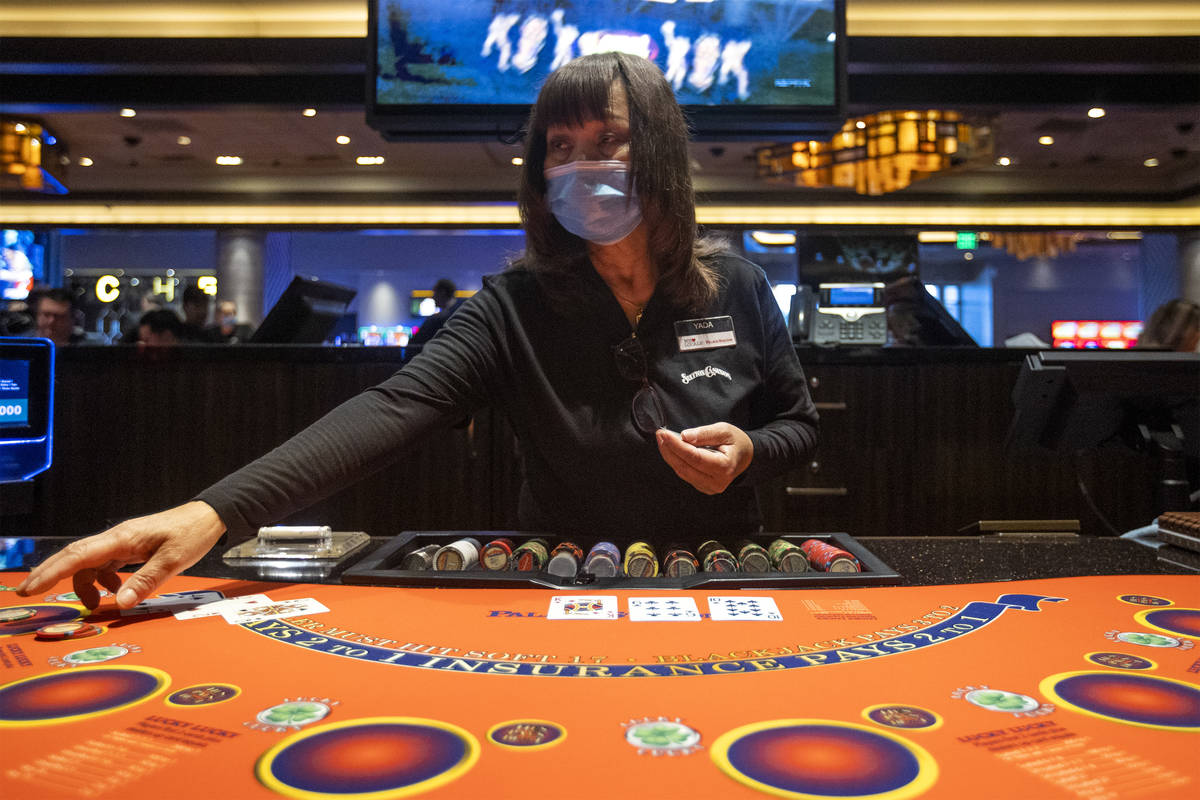 A blackjack dealer wears a mask while she deals a game at Palace Station as casinos have reopen ...