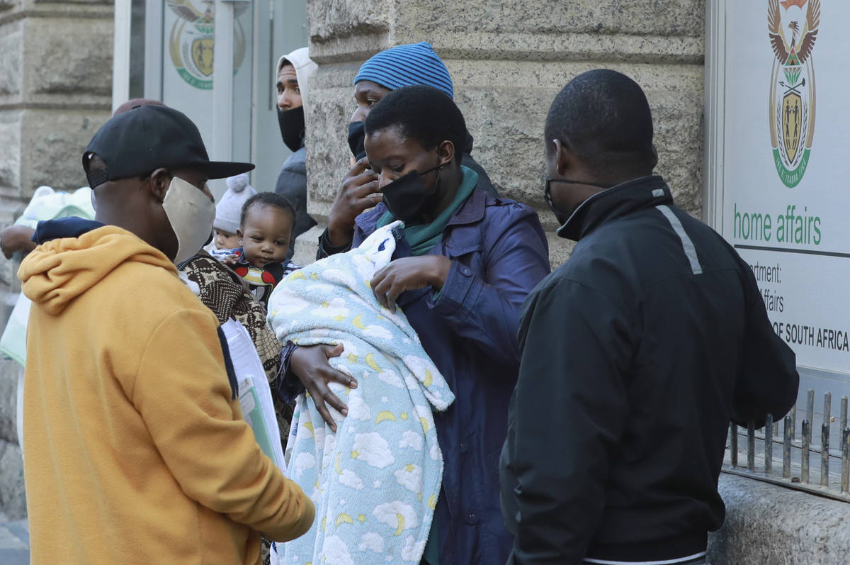 Parents wearing protective masks wait to register their newly-born child at the Home Affairs of ...