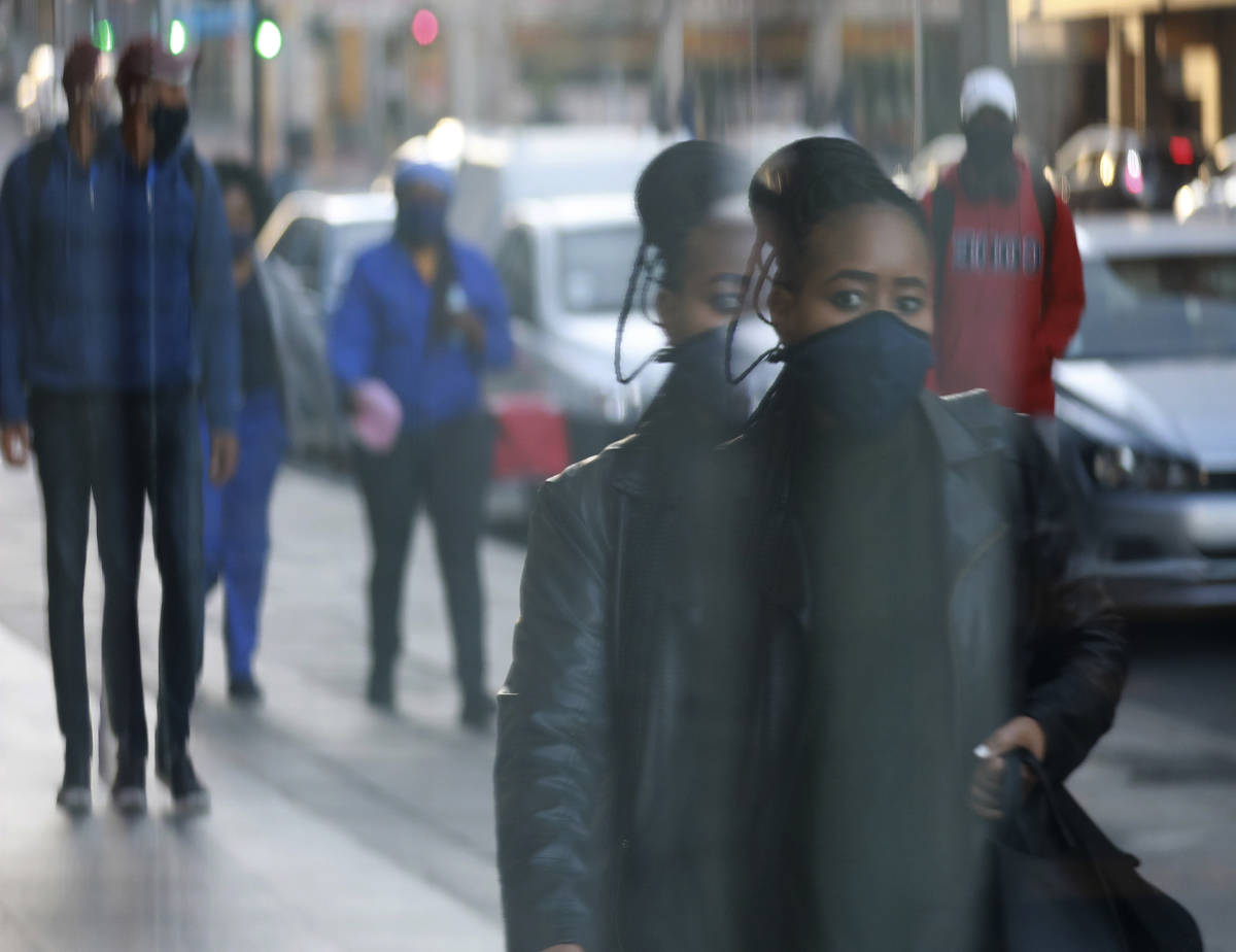 The reflection of a woman wearing a face mask is caught in the window of a shop in Cape Town, S ...