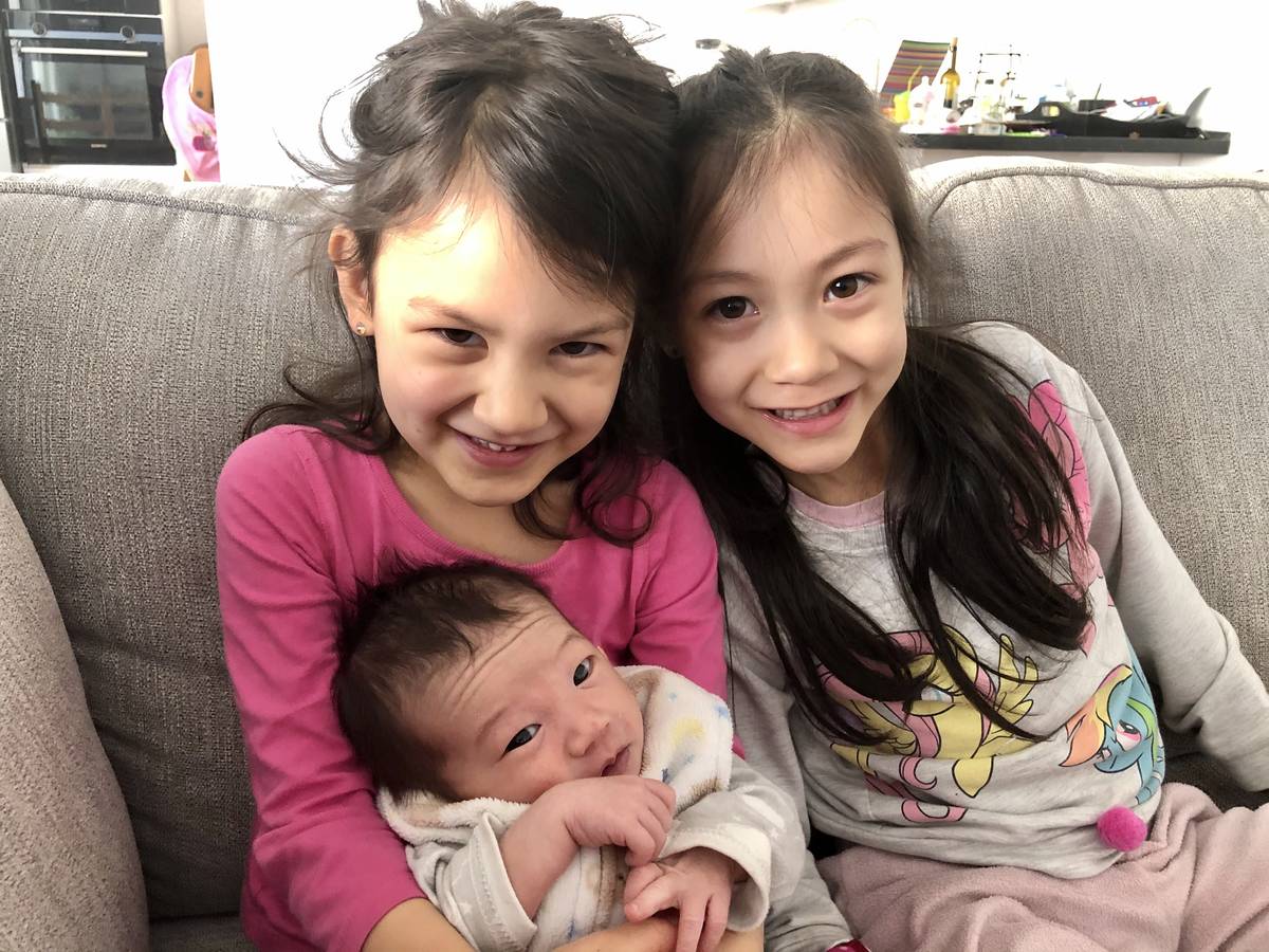 (From left to right) Lorelai Stein, 7, and Audrey Stein, 4, hold their newborn sister, Sadie, i ...