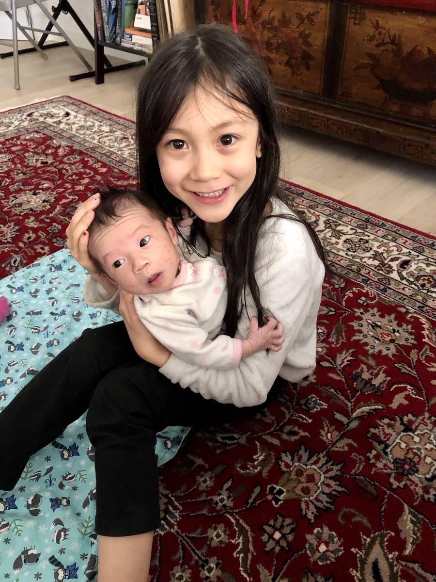 Lorelai Stein, 7, holds her newborn baby sister, Sadie. Sadie was born at home April 1 in Madri ...