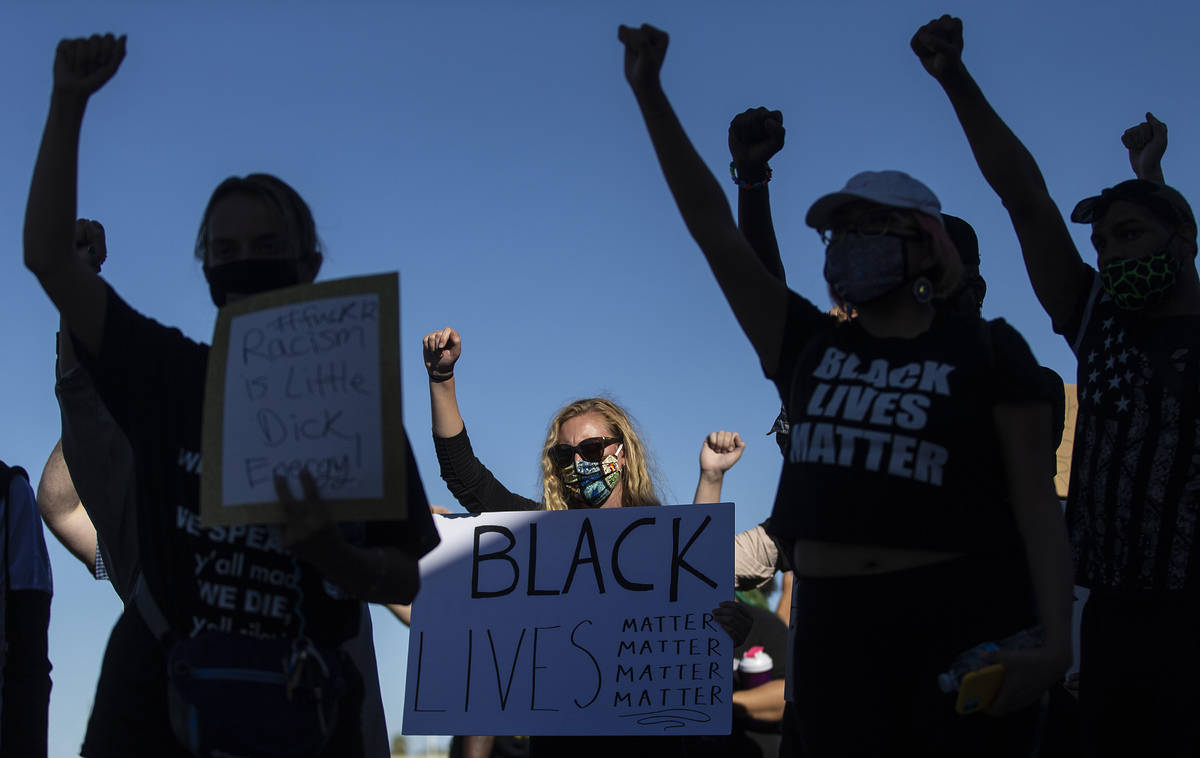 Protesters hold signs during a Juneteenth rally organized by Black Lives Matter on Friday, June ...