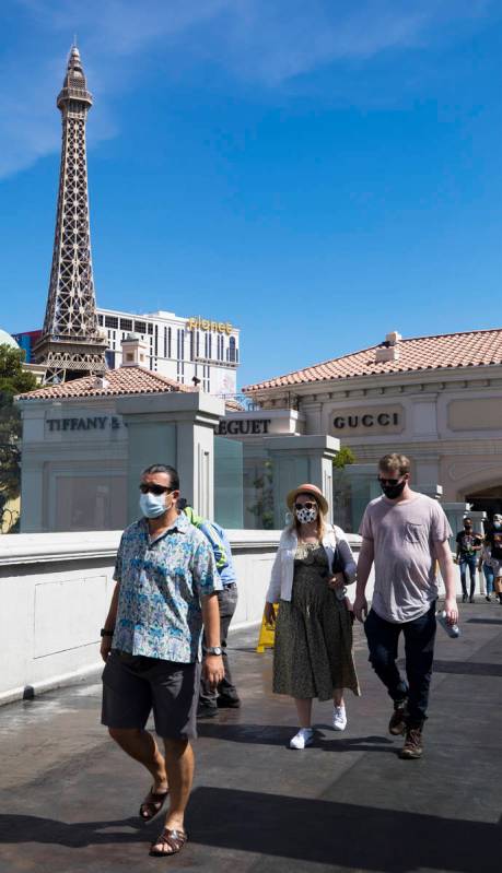 Visitors cross a pedestrian bridge on the Strip in Las Vegas, Sunday, June 21, 2020. (Rachel As ...