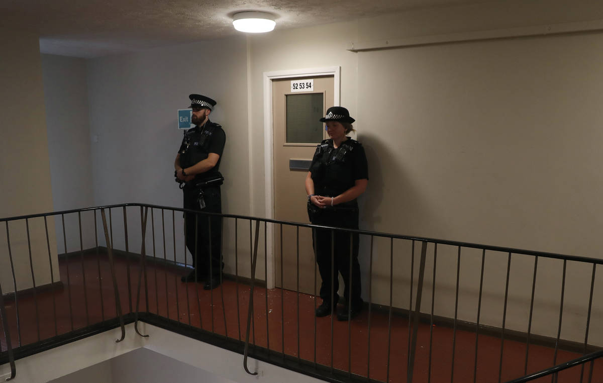 Police stand guard outside a top floor flat on Basingstoke Road that was raided by police a day ...