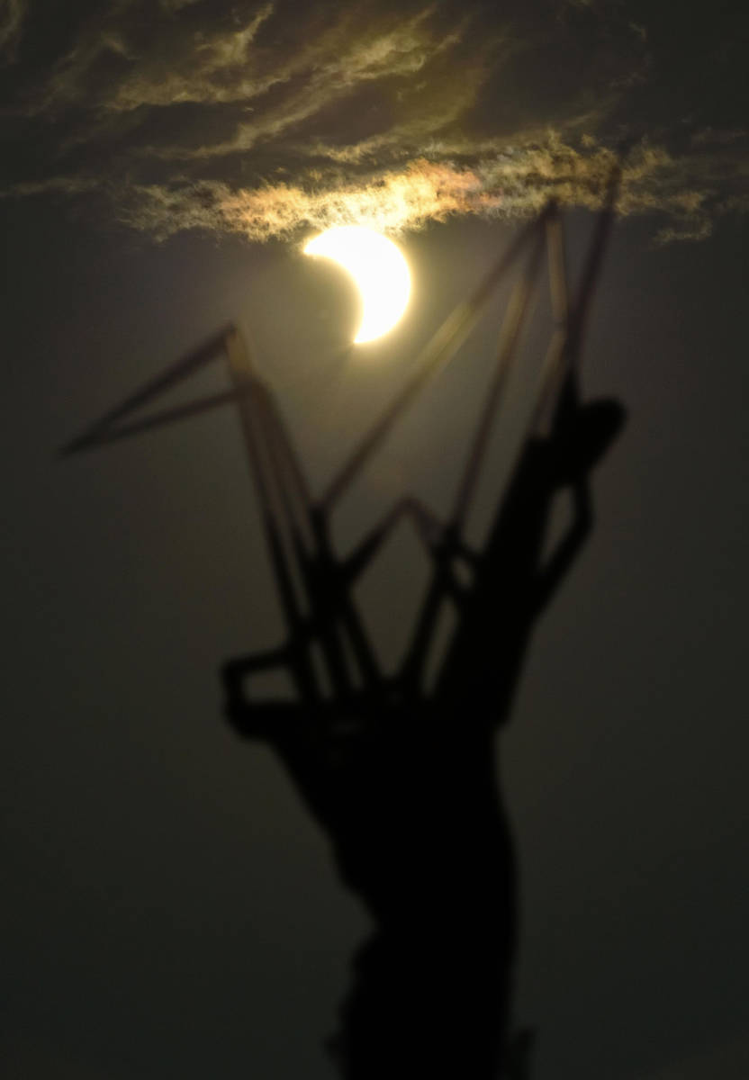 A partial solar eclipse is seen over the Children's Peace Monument at Hiroshima Peace Memorial ...