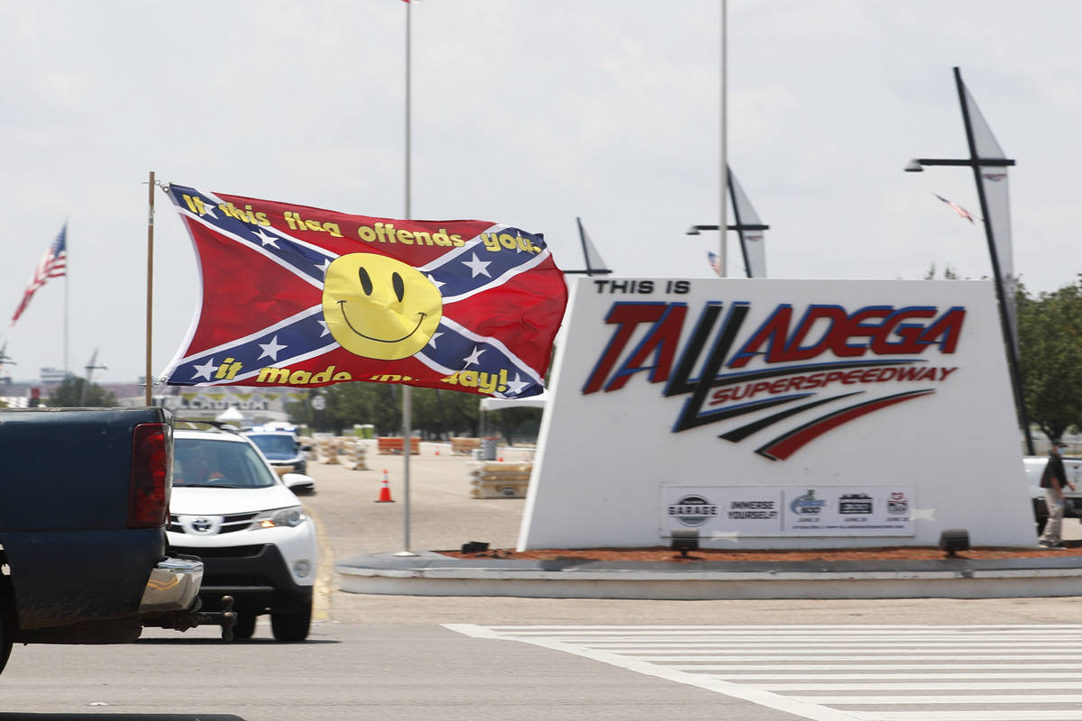 Race fans fly Confederate battle flags and United States flags as they drive by the entrance to ...